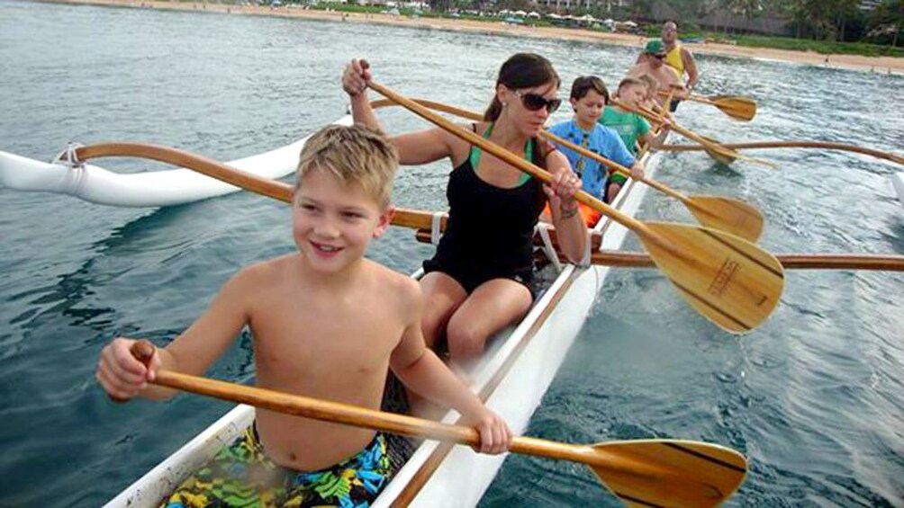 A family rides in an outrigger canoe