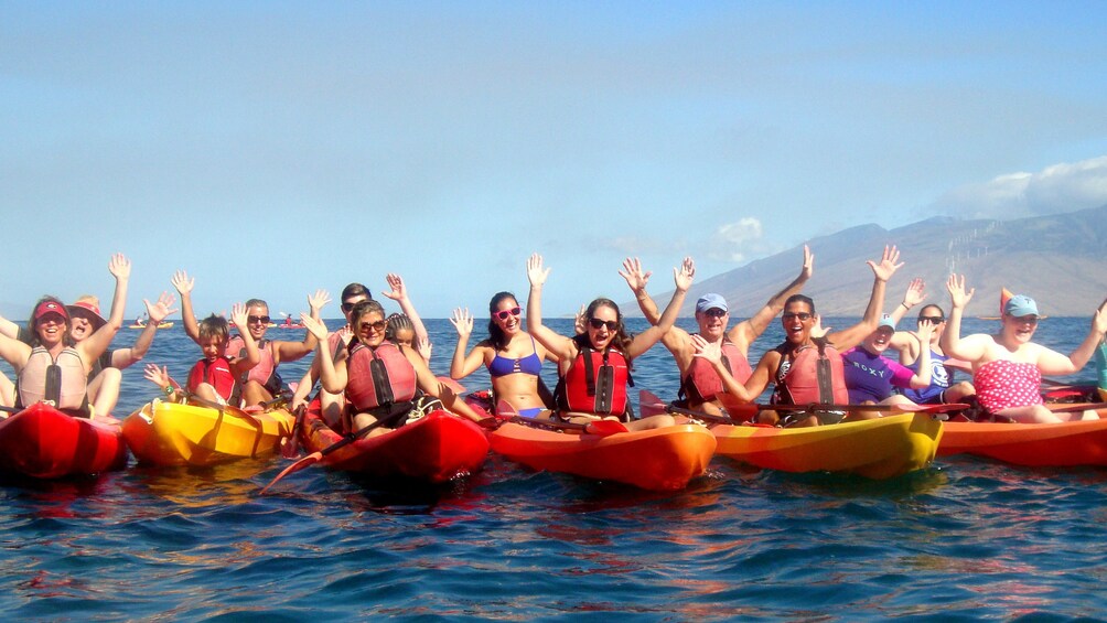 A Kayak Snorkel Tour poses with their arms in the air.