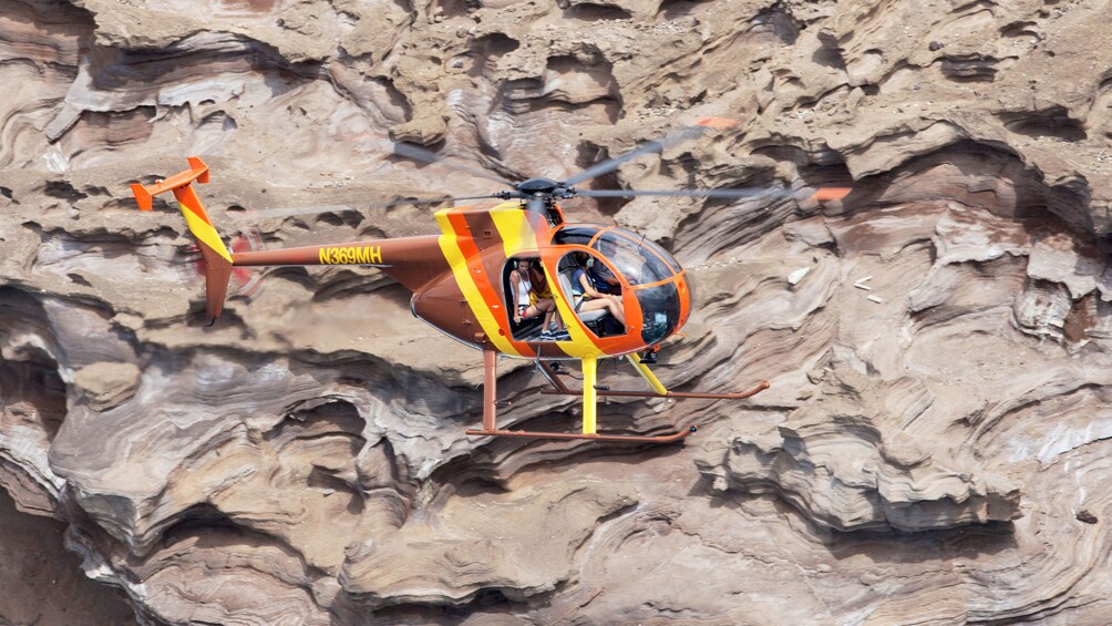 Aerial view of a helicopter with doors off flying by the rock formations in Hawaii 