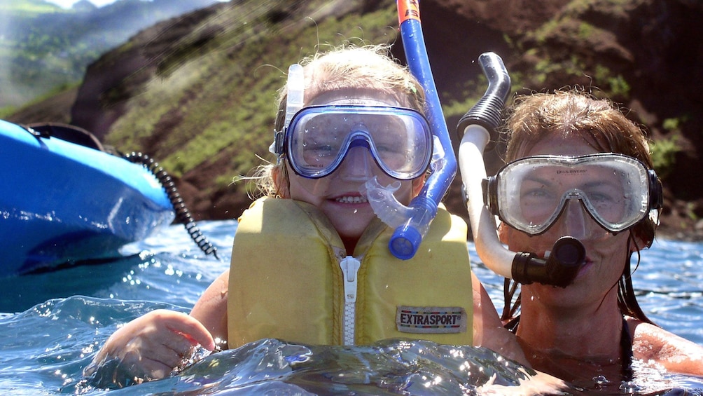 Mom and daughter snorkeling near their kayak in Maui