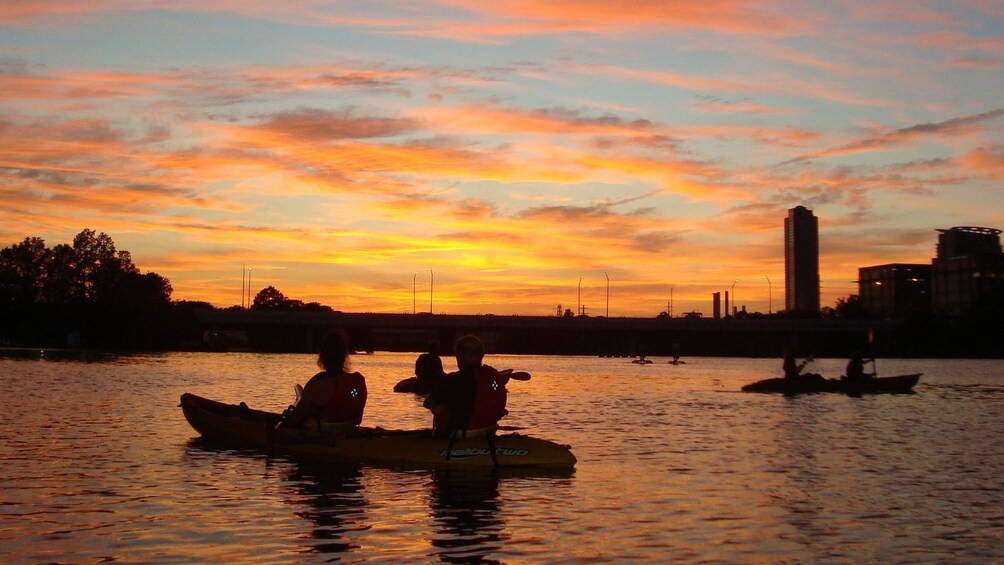 Silhouette of people on boats at sunset.