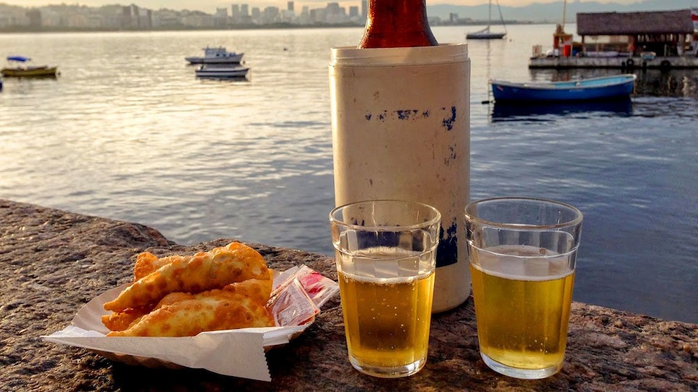 Basket of fried meat and two glasses of Beer on a ledge overlooking Sunset over Rio De Janeiro 