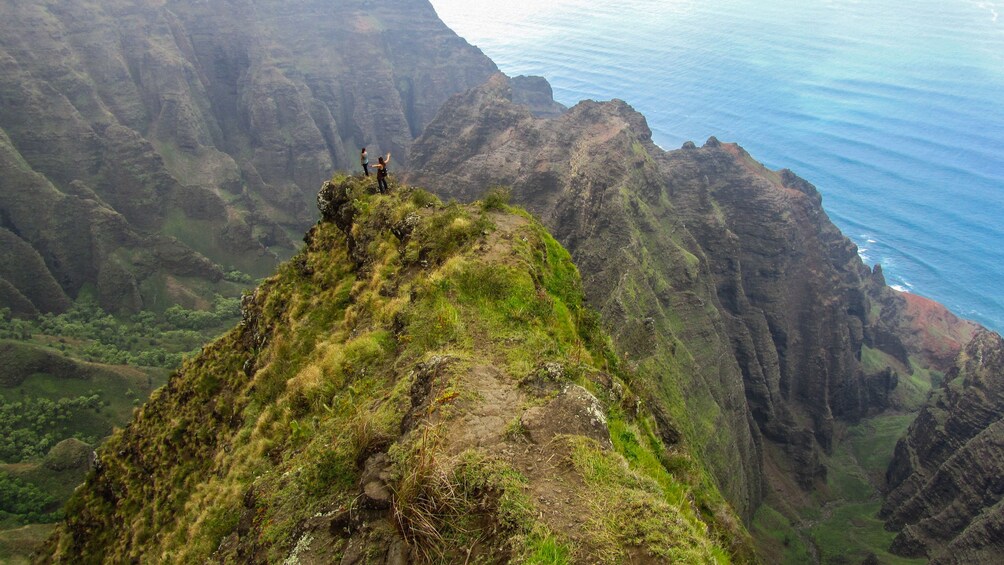 Aerial view of Nā Pali showing two hikers at mountain peak