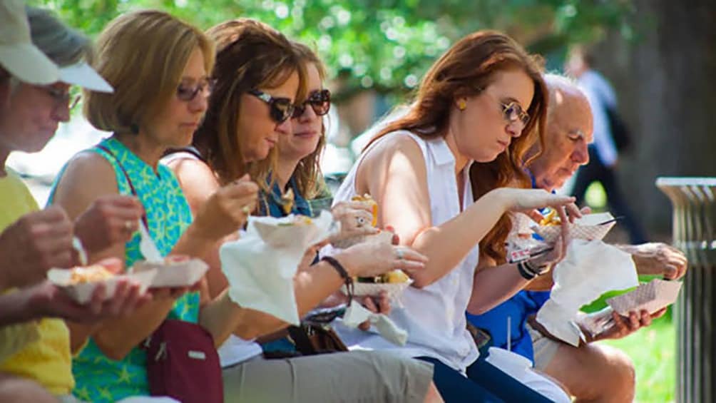 Show item 1 of 8. group eating lunch on a bench in Savannah