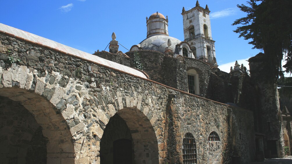 Angled view of historic building with stone bridge in view.