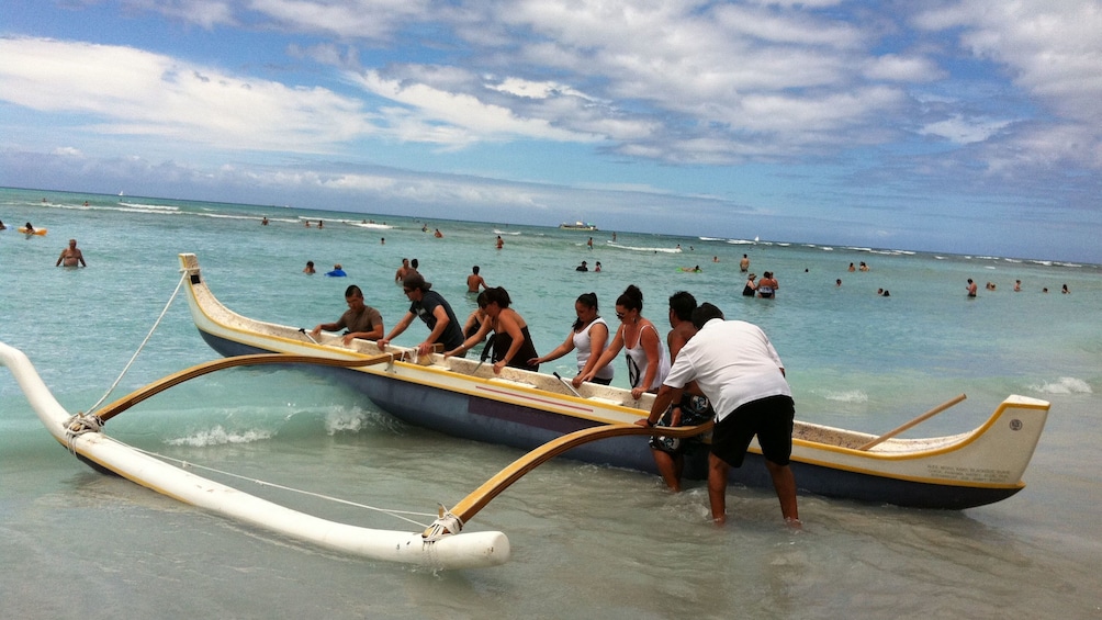 Canoe being pushed out into water in oahu
