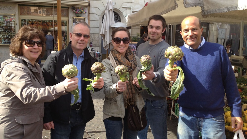 Tour group holding up artichokes at a market in Rome