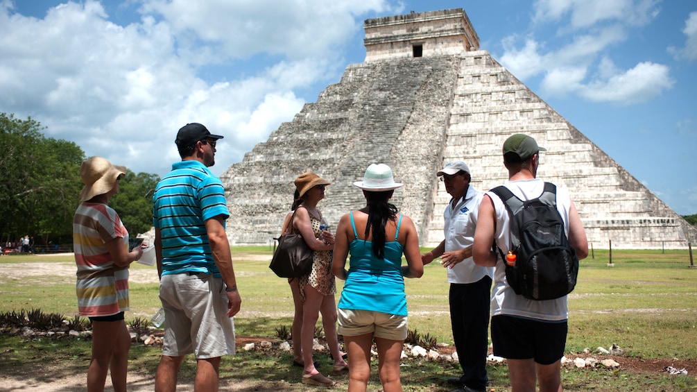 Private tour guide and group of people in front of a pyramid of Chichen Itza