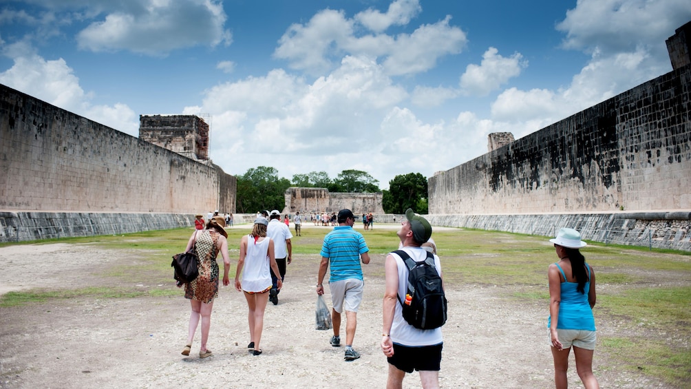 A group of people walk through the ruins of Chichen Itza