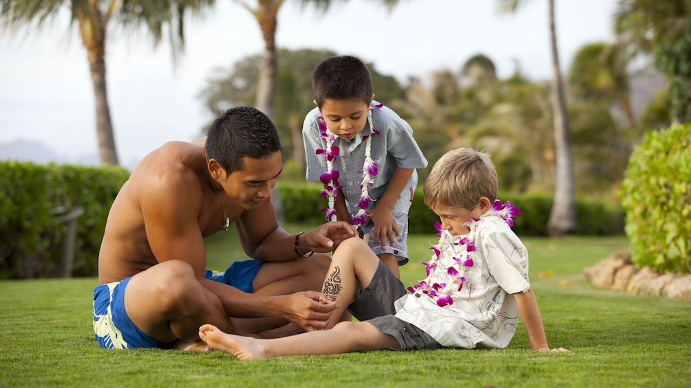 Man painting tribal art on young boy in Oahu