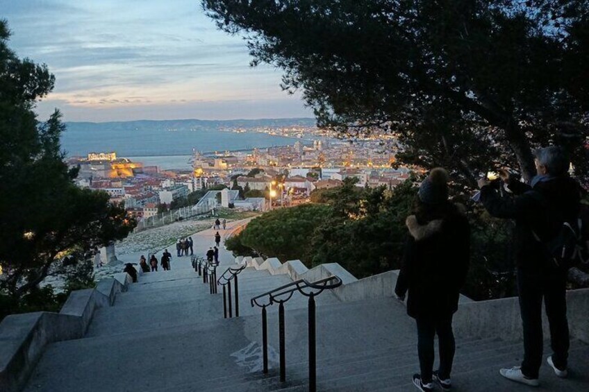 Two hikers admiring the city that lights up at sunset