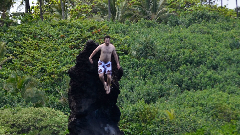 Man jumping into a waterfall in Hana