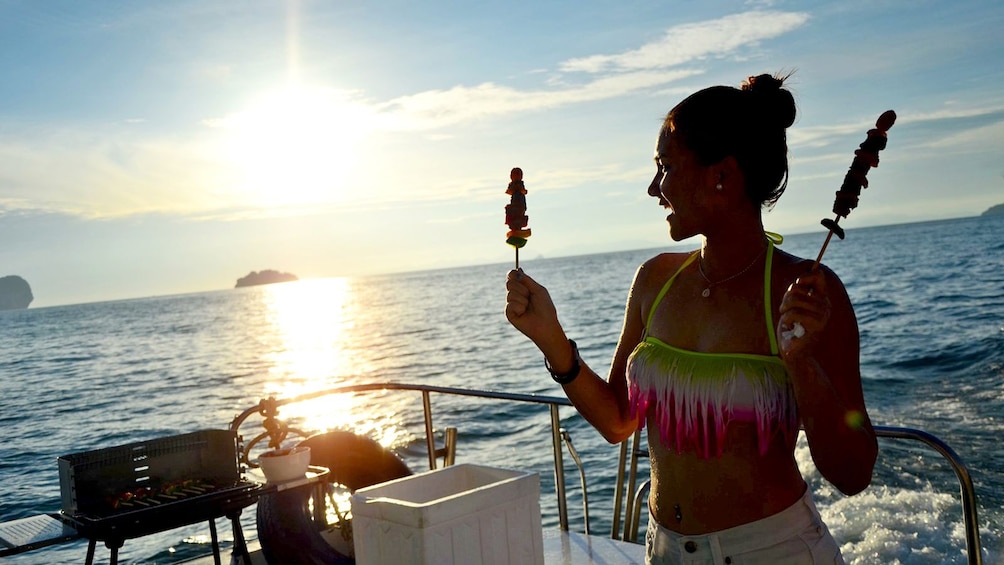 woman holding skewers on a catamaran in Thailand
