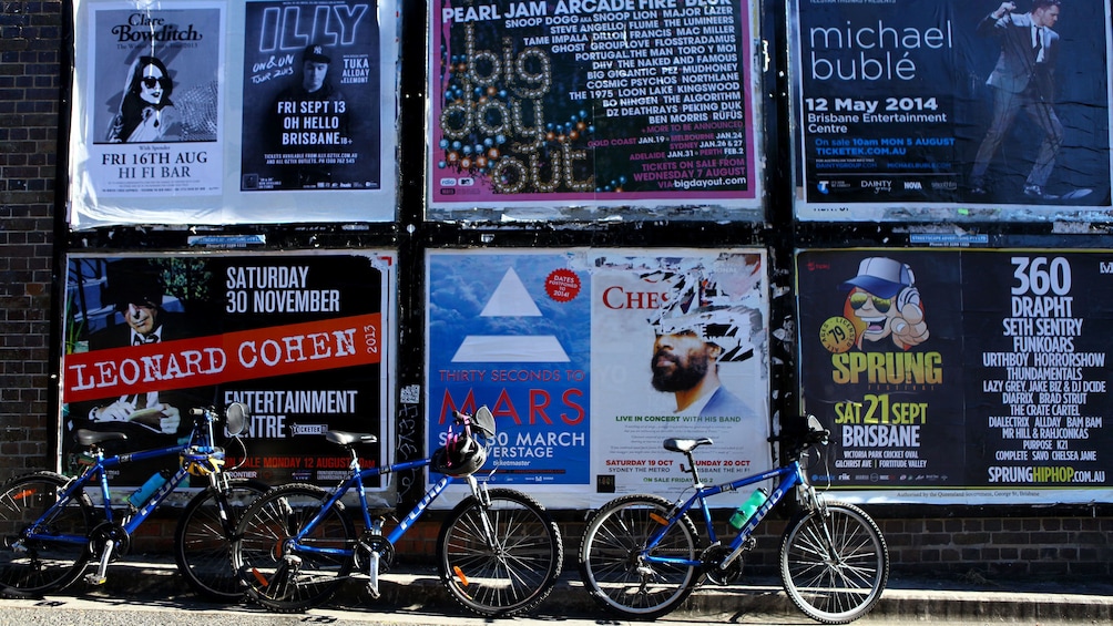 Bicycles parked by wall of posters in Brisbane