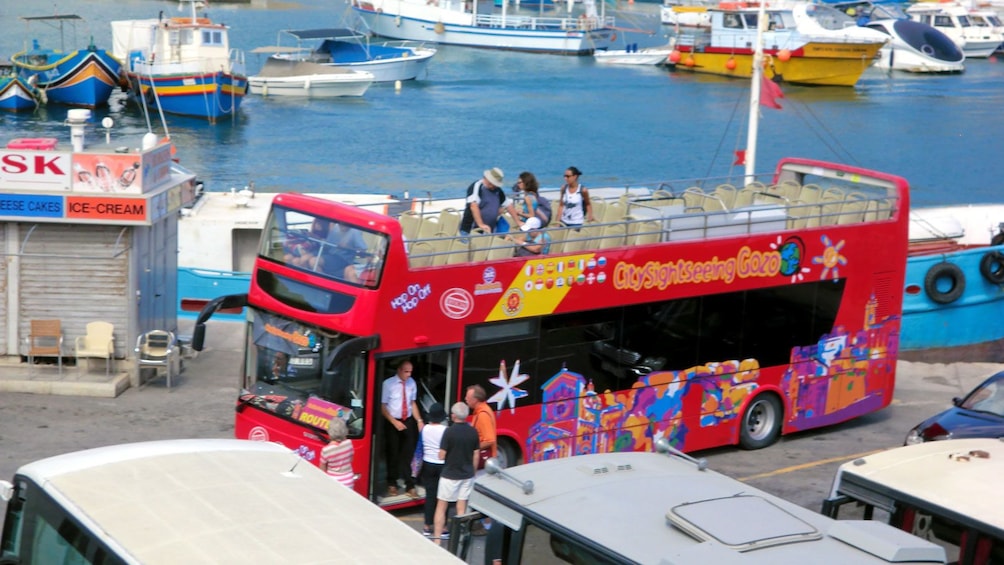 passengers boarding a red double decked bus in Gozo
