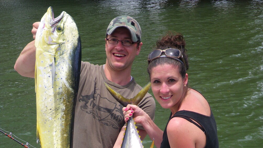 man and woman holding up their catch in Kauai