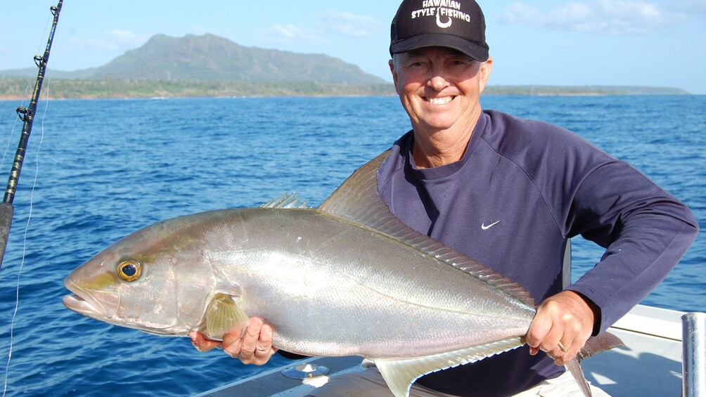 man with large fish on boat in Kauai
