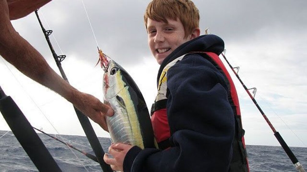 boy with his fish on boat in Kauai