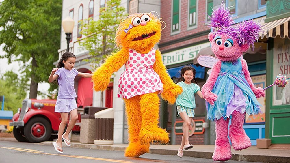 Show item 4 of 8. Girls skipping with costume characters in Sesame Place