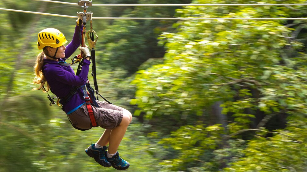 A woman ziplining through a forest in Hawaii