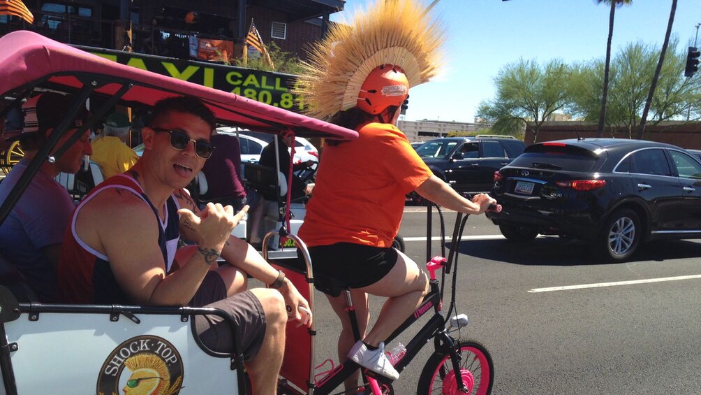 Group of young people traveling to pub by pedicab during the day.