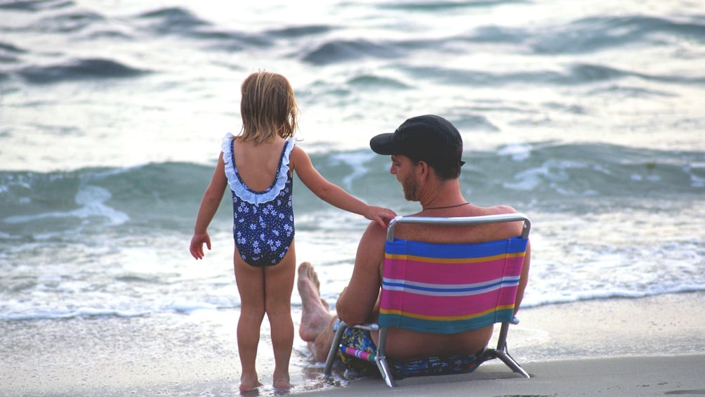Father and daughter on beach chairs relaxing on the Maui coast
