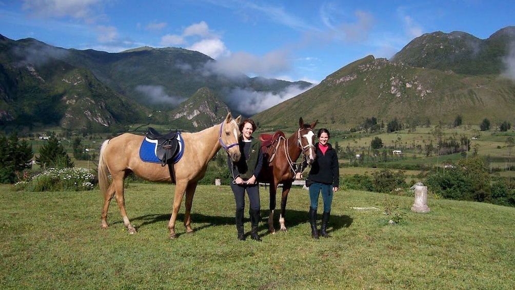 Women with horses and green mountains in the background in Quito