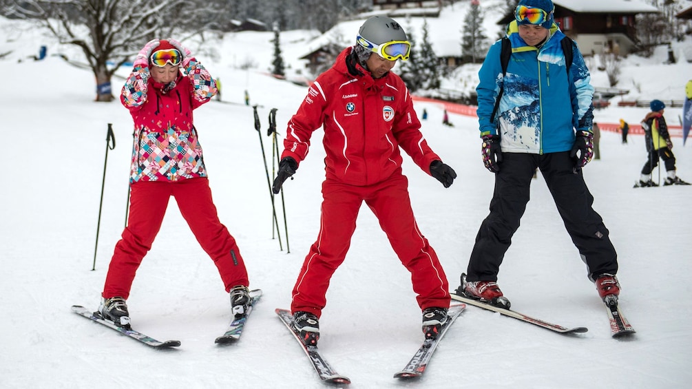 An instructor teaching two people how to ski in the Swiss Alps