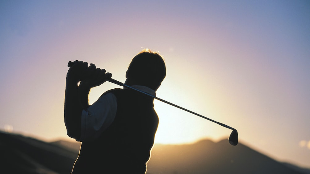 Silhouette of golfer at sunset.