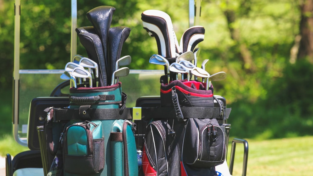 Close up of several golf clubs in bags.