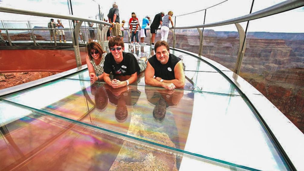 Family posing together on floor of skywalk observation deck.