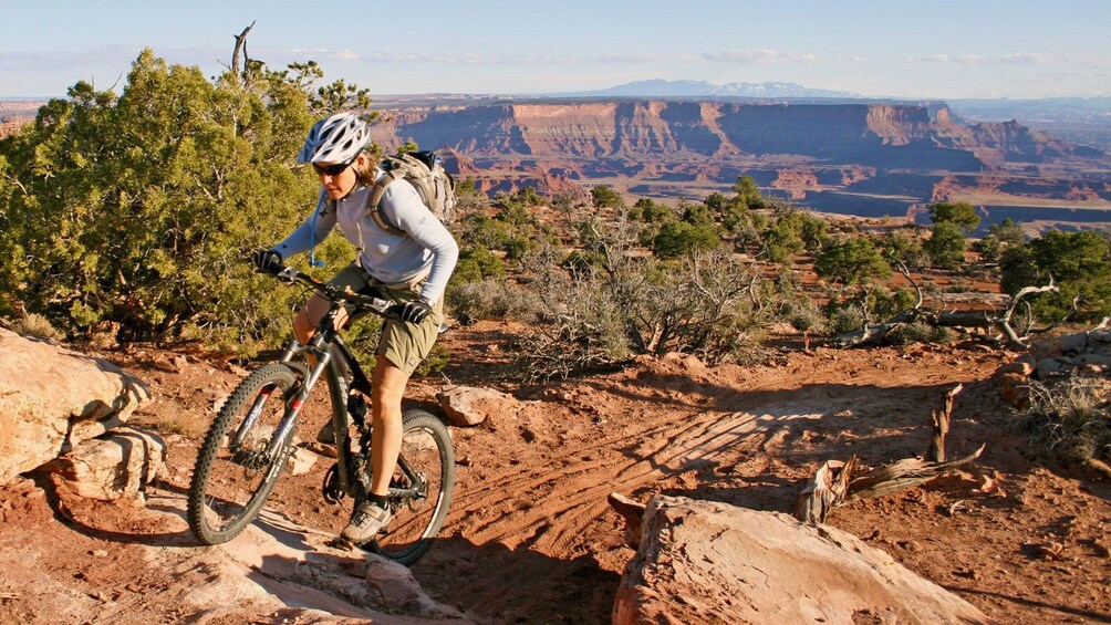 woman rides bike up a dirt trail in Green River