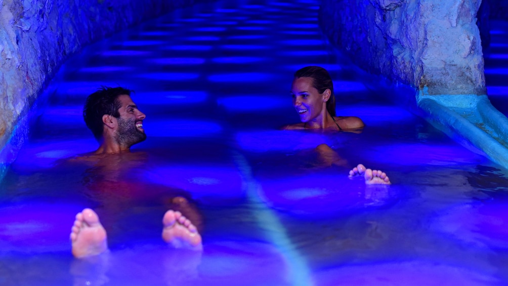 Two people float in blue water in a lagoon