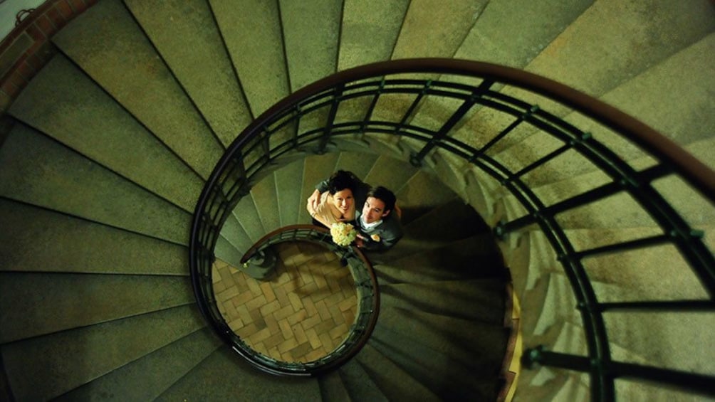 Indlæs billede 1 af 5. Looking down at a bride and groom at the bottom of a spiral staircase in Coppenhagen
