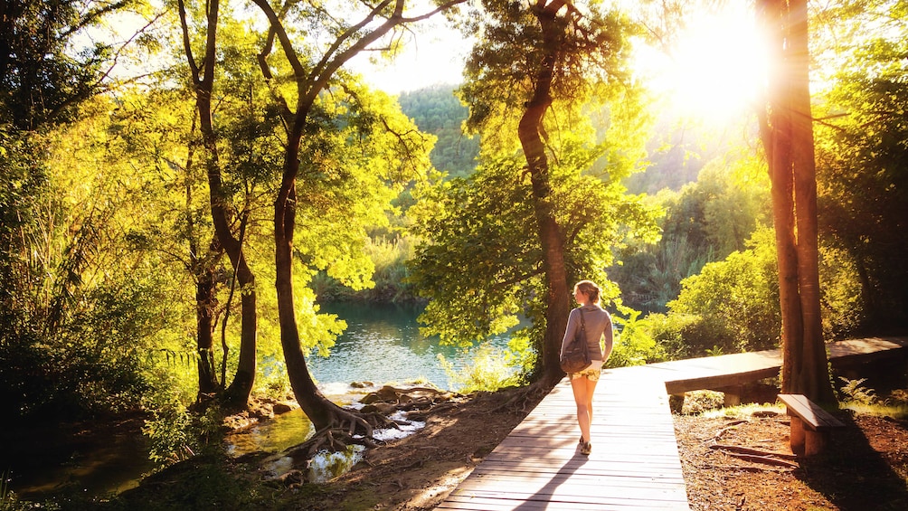 Foto 3 van 8. Sunset view of Krka Waterfalls Park with woman observing beautiful scenery.