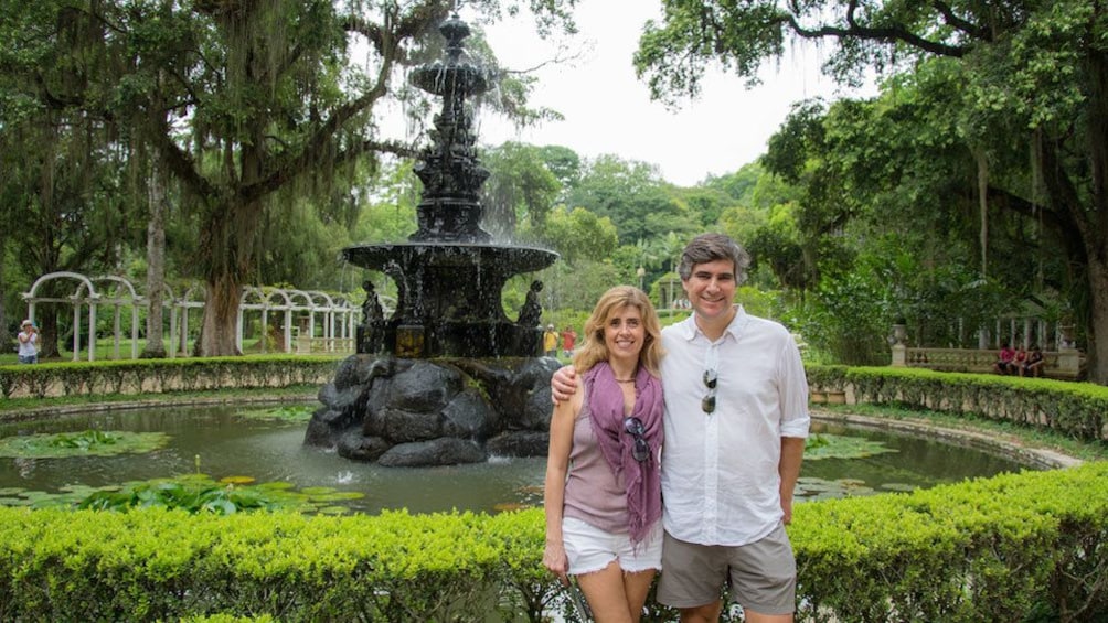 Two people pose next to a fountain