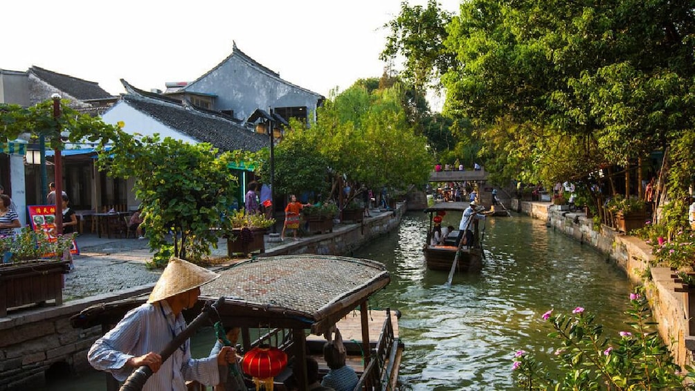 Show item 1 of 10. Passenger pole boats are pushed down a Shanghai canal.