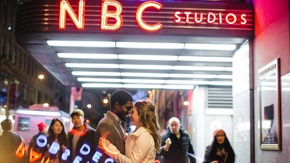 Couple standing in front of NBC Studios at night in New York 