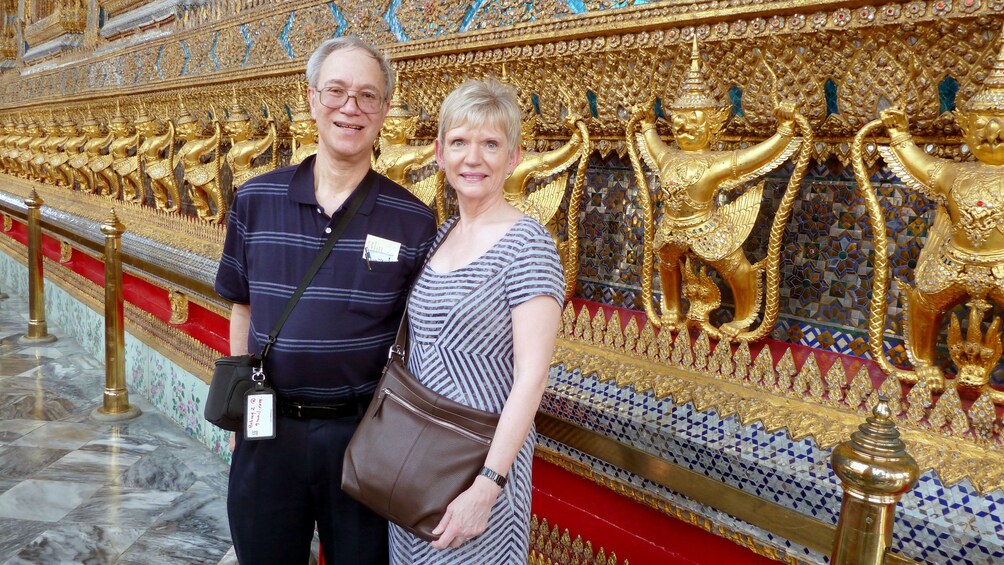 Two people infront of an ornate facade in bangkok
