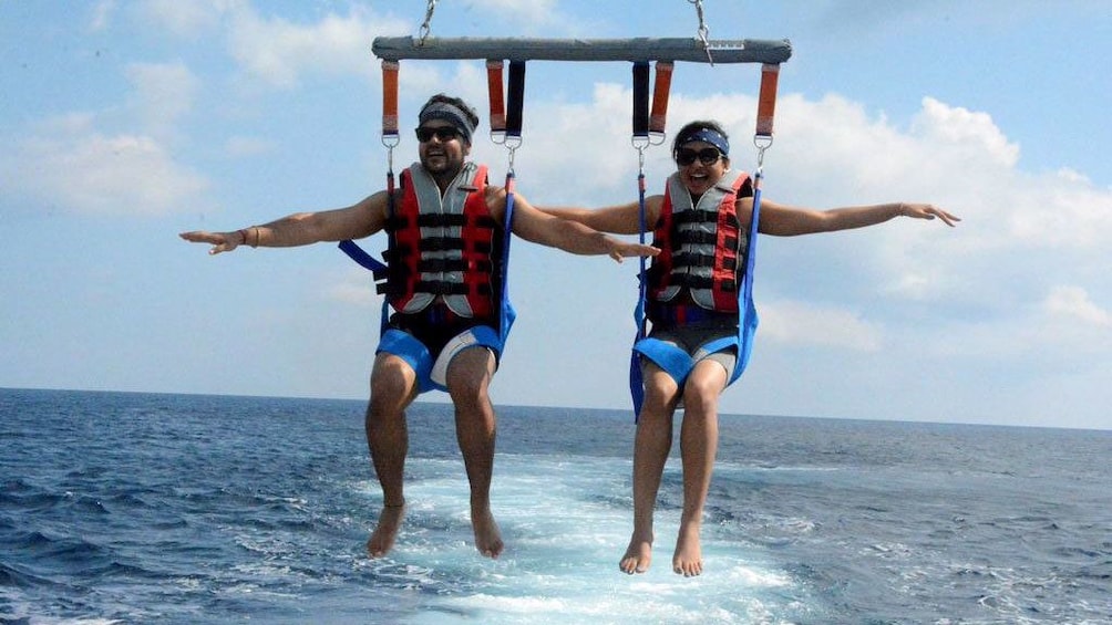 Charger l’élément 2 sur 5. Parasailing couple low over the water in Santorini