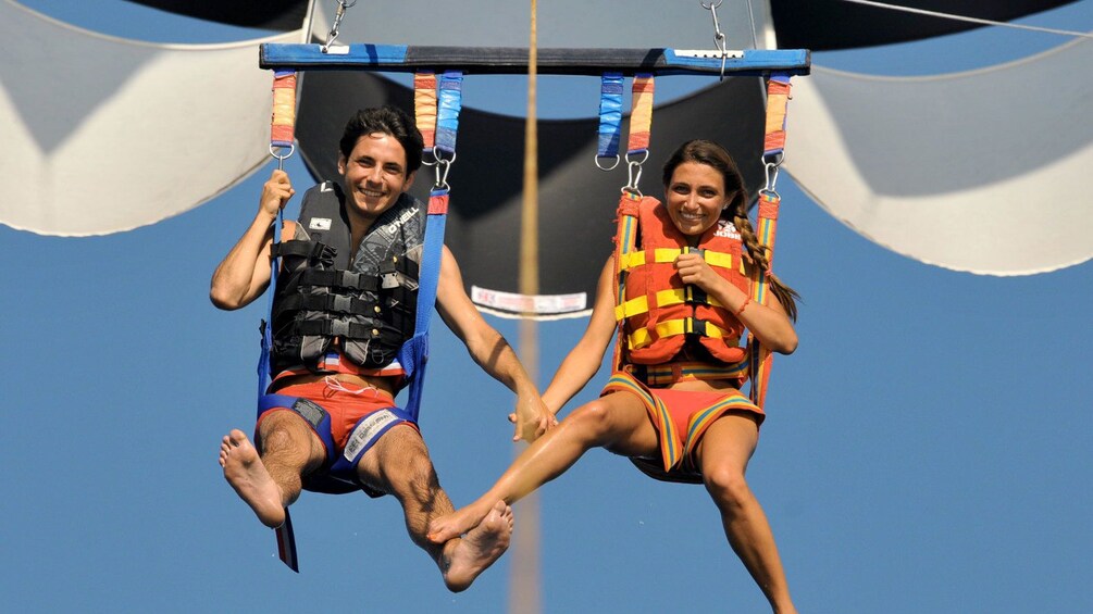 Charger l’élément 1 sur 5. Parasailing couple holding hands in Santorini