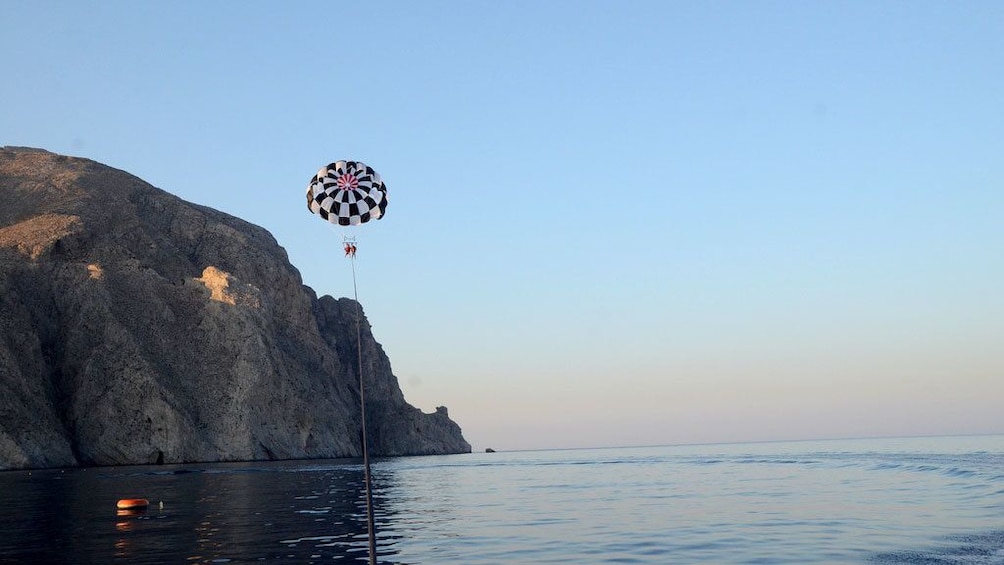 Charger l’élément 4 sur 5. Parasailer high in the air near coastal cliffs in Santorini