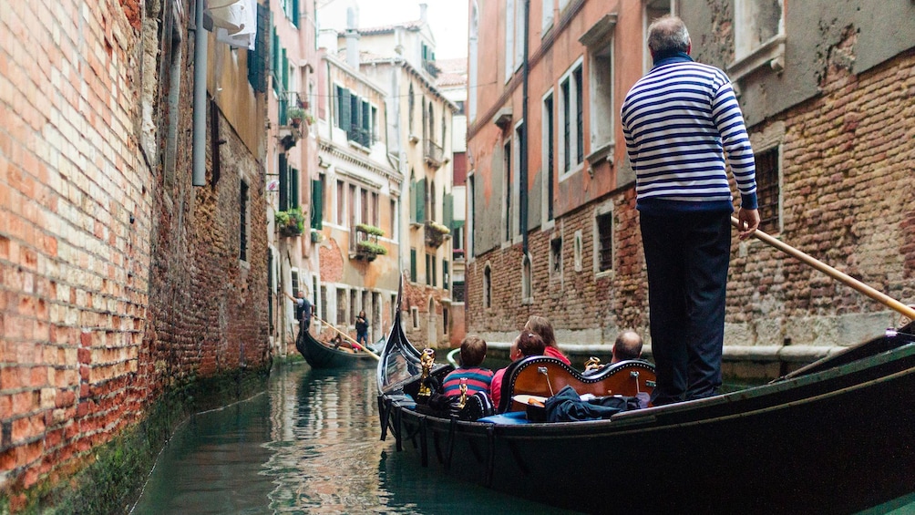 Man takes Gondola through canal in Venice