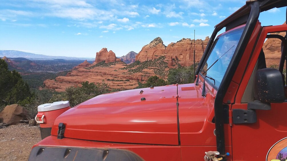 Red safari jeep with mountains in the distance.