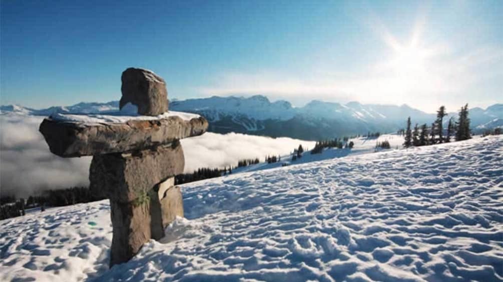 Inukshuk rock sculpture on a snowy hill in Whistler