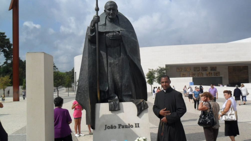 Priest next to image of Joao Paulo II
