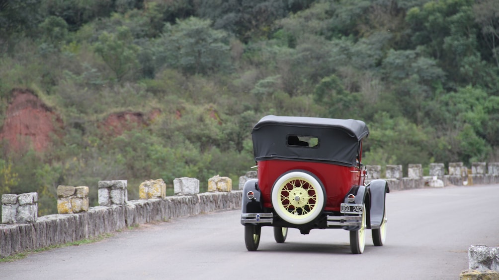 Show item 3 of 5. antique red car from behind on the road