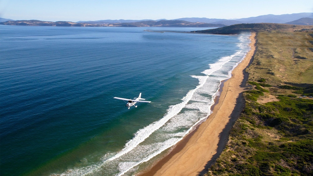 Show item 4 of 5. Aerial view of the plane flying above the waters on the Learn to Fly Discovery Package at Par Avion Wilderness Tours in Hobart and Surrounds, TAS, Australia