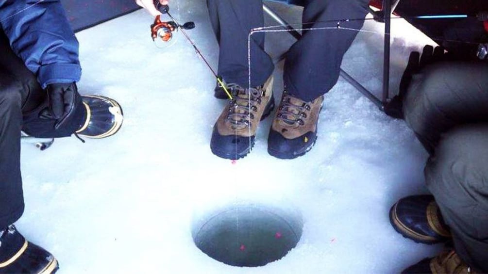 People fishing through a hole in the ice in Fairbanks