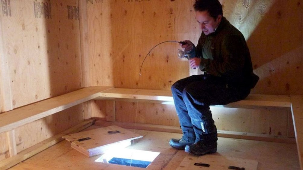 Man ice fishing inside a shelter in Fairbanks